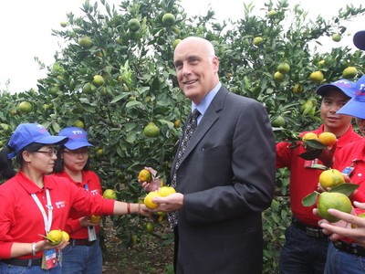 沃爾瑪中國公司事務(wù)高級副總裁博睿（中）考察大理項目基地，并同沃爾瑪員工志愿者一起幫助受助農(nóng)戶收獲成熟的柑橘。